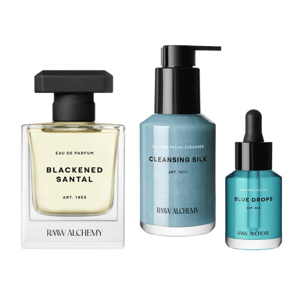 RAAW Alchemy Award Winning Bundle featuring Blackened Santal Eau de Parfum, Cleansing Silk facial cleanser, and Blue Drops facial oil on a transparent background.