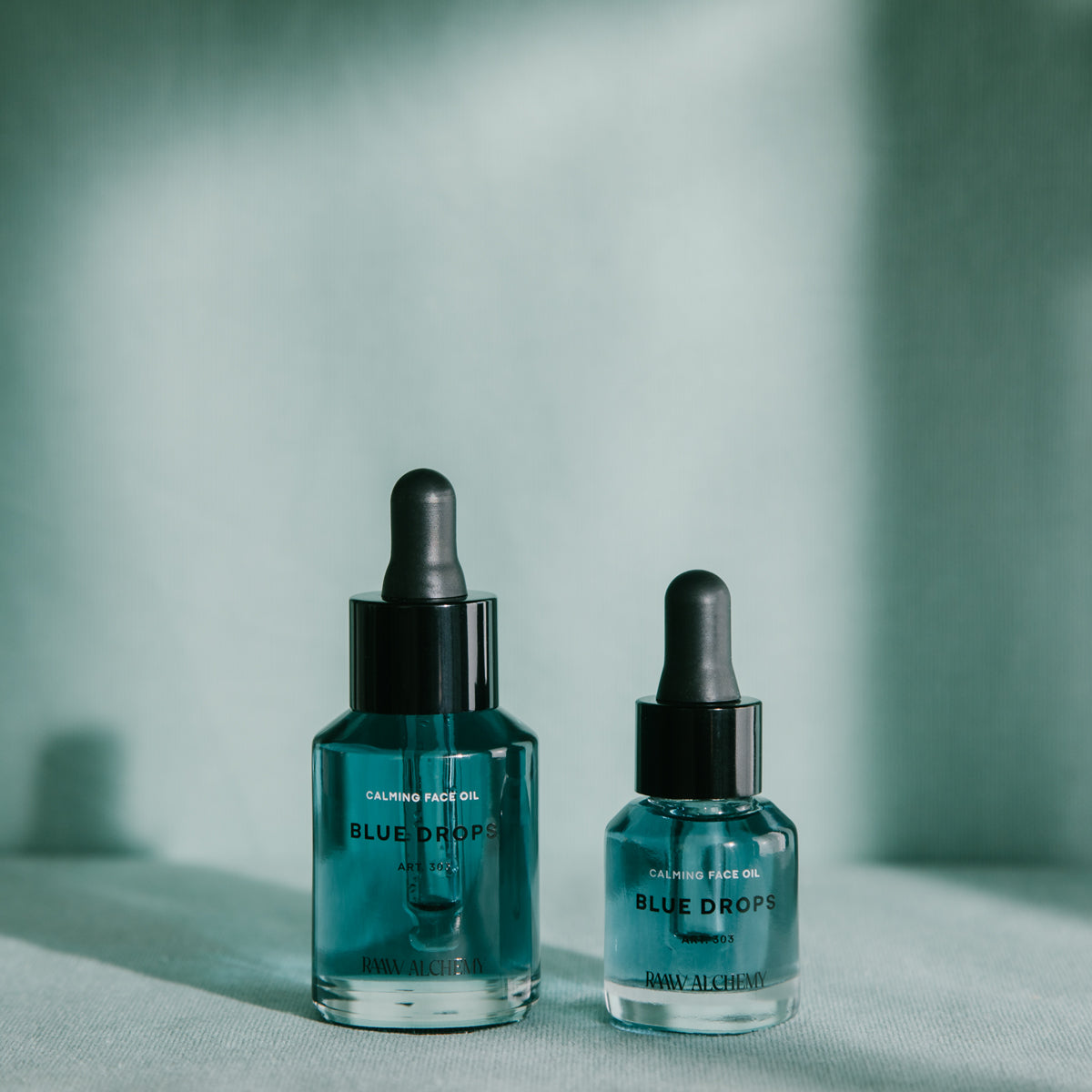 Two sizes of RAAW Alchemy Blue Drops calming face oil displayed in a clean, aesthetic lighting.